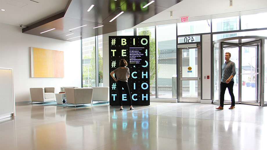 Monolithic media display in a bright, open building lobby.